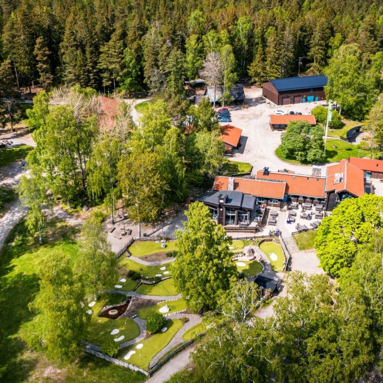 bruna hus, träd. gräsmattor och minigolfbana fotat uppifrån.