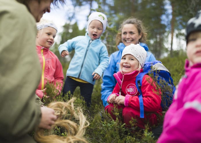 glada barn i färgglada kläder lyssnar på skogsmullei skogen