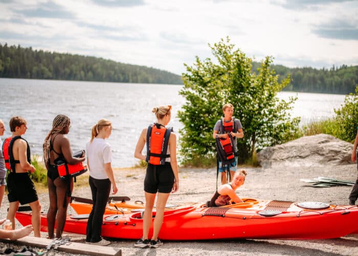 En grupp människor som står runt en röd kajak.