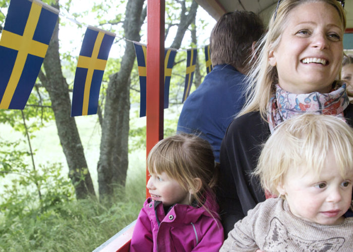 Glad kvinna åker tufftuff-tåg med två barn