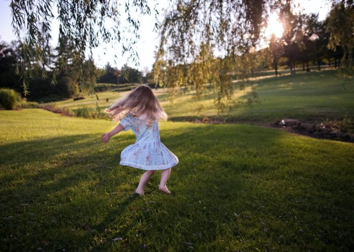 Liten flicka i klänning dansar på en gräsmatta