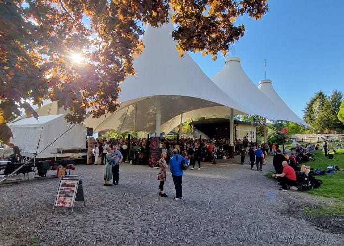 Danskväll utomhus på dansbana under vitt stort segeldukstak, himlen är blå.