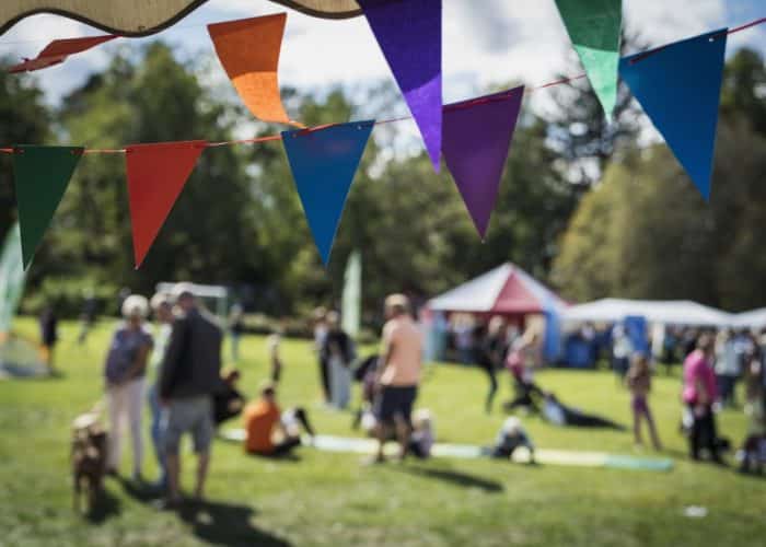 Färgglada vimplar i fokus, i bakgrunden människor i rörelse som sitter och går